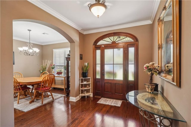 foyer entrance with baseboards, ornamental molding, wood finished floors, arched walkways, and a notable chandelier