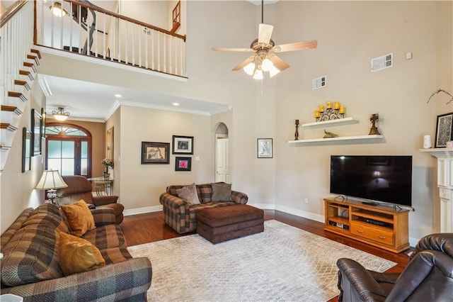 living area featuring visible vents, ornamental molding, a ceiling fan, wood finished floors, and arched walkways