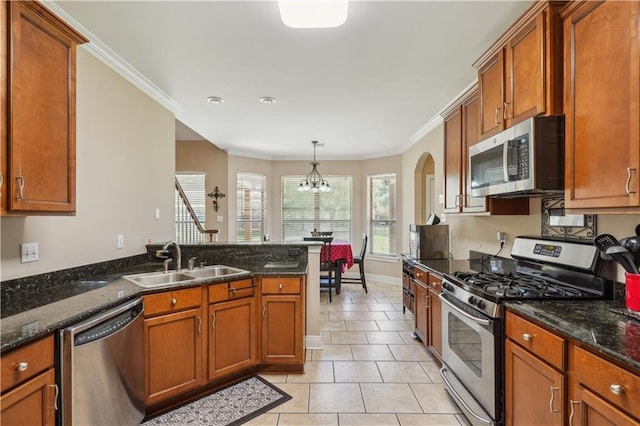 kitchen with a notable chandelier, brown cabinets, appliances with stainless steel finishes, and a sink