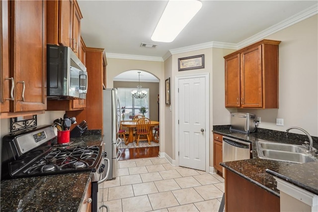 kitchen featuring visible vents, arched walkways, a sink, appliances with stainless steel finishes, and brown cabinets