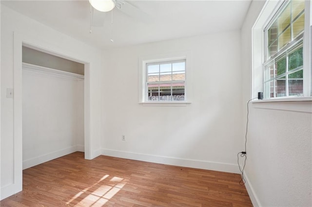 unfurnished bedroom featuring baseboards, wood finished floors, a closet, and a ceiling fan