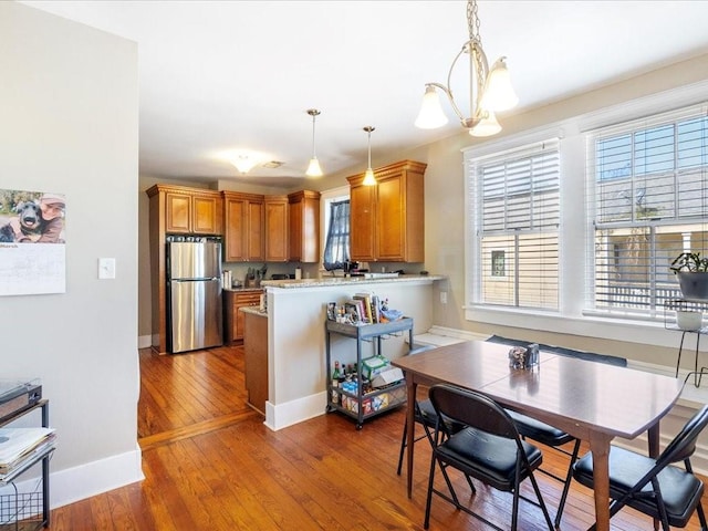 311214 General Taylor St, New Orleans, LA 70125 - kitchen with freestanding refrigerator, brown cabinets, a peninsula, hardwood / wood-style floors, and pendant lighting