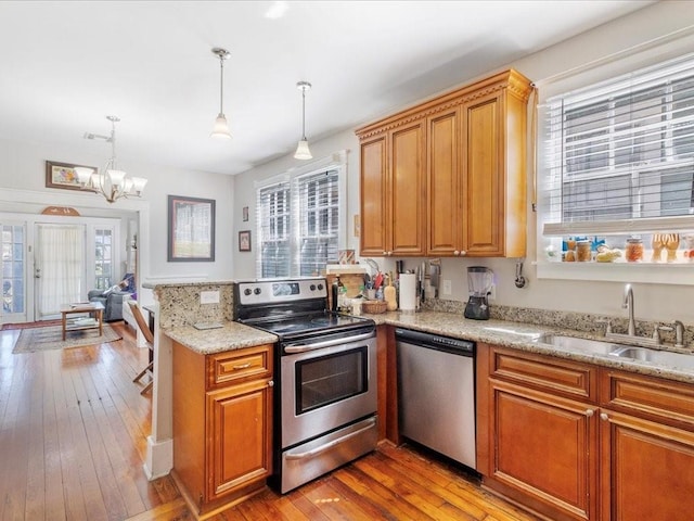 311214 General Taylor St, New Orleans, LA 70125 - kitchen featuring stainless steel appliances, light wood finished floors, brown cabinetry, and decorative light fixtures
