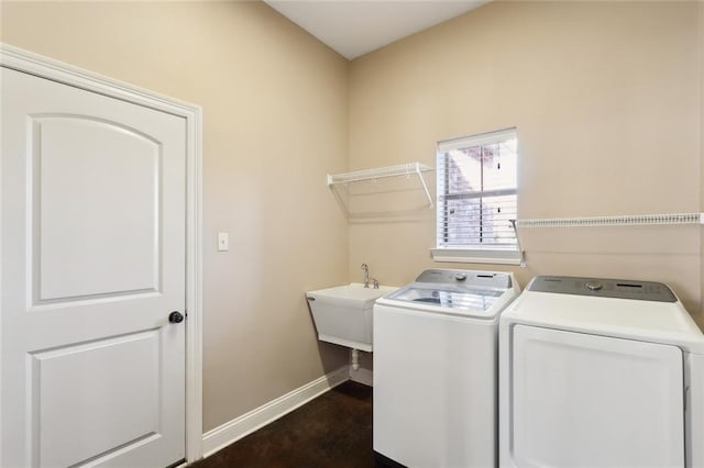 laundry area featuring baseboards, a sink, laundry area, and washer and clothes dryer