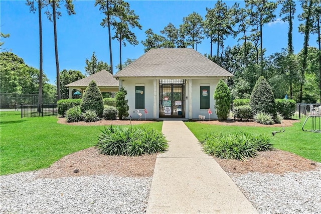 view of front facade with a front lawn, stucco siding, and fence