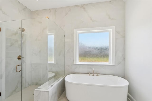 bathroom featuring a freestanding tub, a marble finish shower, and tile walls