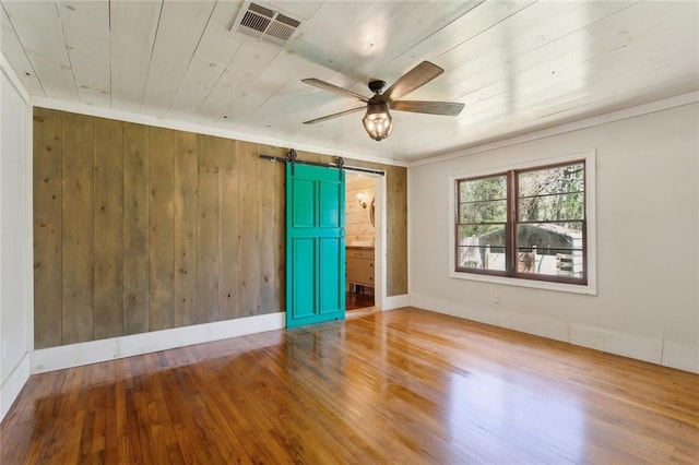 1612 Mossy St, Covington, LA 70433 - empty room with wood finished floors, visible vents, ceiling fan, a barn door, and wooden ceiling