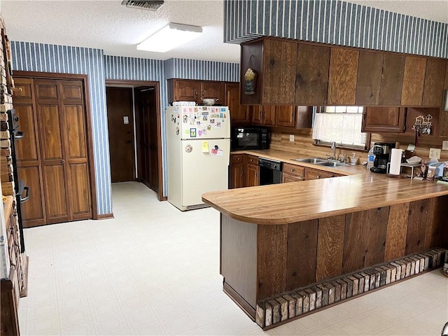 137 Nolan Dr, La Place, LA 70068 - kitchen featuring a sink, a textured ceiling, black appliances, wallpapered walls, and light floors