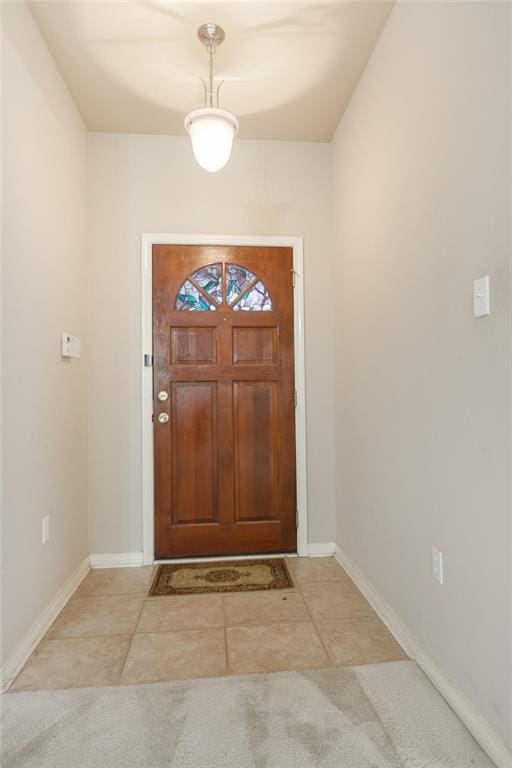 foyer entrance with light tile patterned flooring, light carpet, and baseboards