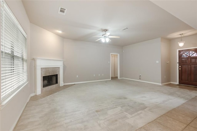 unfurnished living room with a ceiling fan, a fireplace, baseboards, light colored carpet, and visible vents