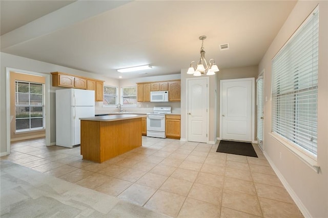 kitchen with light tile patterned flooring, white appliances, baseboards, a kitchen island, and an inviting chandelier