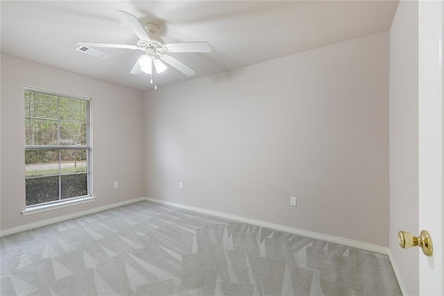spare room featuring light carpet, baseboards, visible vents, and a ceiling fan