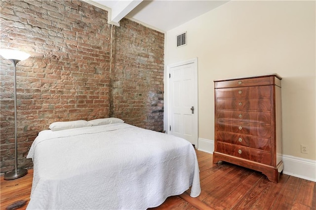 bedroom featuring visible vents, baseboards, beamed ceiling, and wood finished floors