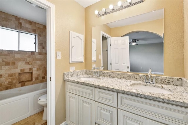 full bathroom with double vanity, toilet, a ceiling fan, and a sink