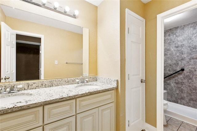 bathroom with double vanity, tile patterned floors, toilet, and a sink