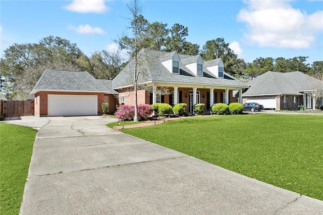 cape cod home featuring brick siding, a garage, driveway, and a front lawn