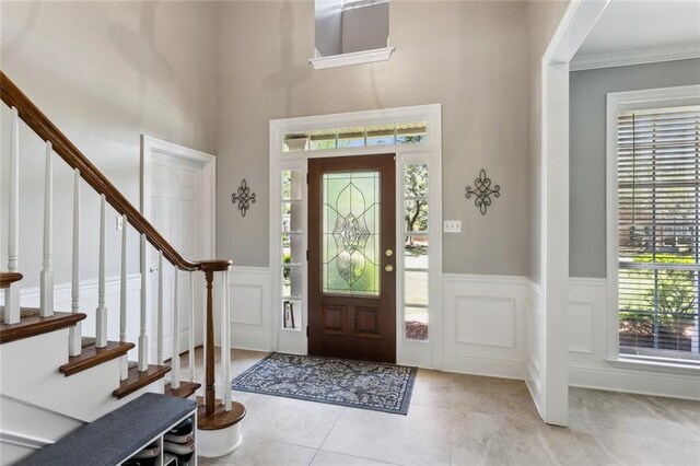 foyer entrance with stairs, a decorative wall, and a wainscoted wall