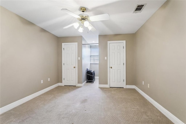 unfurnished bedroom featuring visible vents, baseboards, light carpet, and a ceiling fan