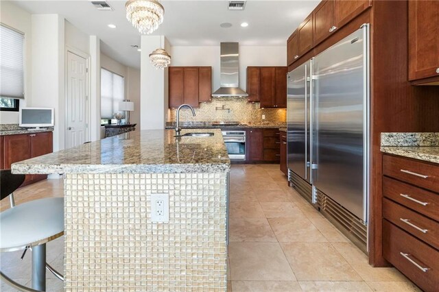 5878 General Haig St, New Orleans, LA 70124 - kitchen featuring stainless steel appliances, wall chimney range hood, decorative backsplash, a chandelier, and light tile patterned floors