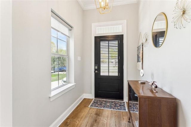 entrance foyer with baseboards, wood finished floors, a chandelier, and ornamental molding