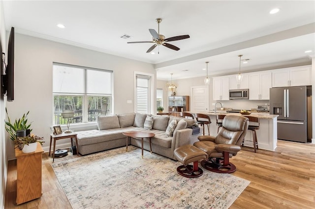 living room with visible vents, recessed lighting, ornamental molding, light wood-type flooring, and a ceiling fan