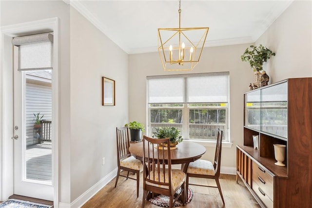 dining space featuring a chandelier, light wood-type flooring, ornamental molding, and baseboards