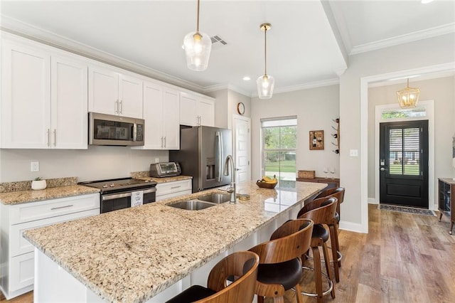 kitchen featuring white cabinets, stainless steel appliances, an island with sink, and a sink