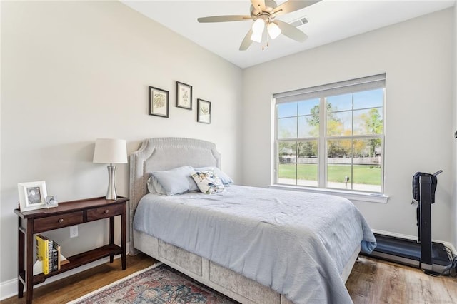 bedroom with baseboards, visible vents, wood finished floors, and a ceiling fan