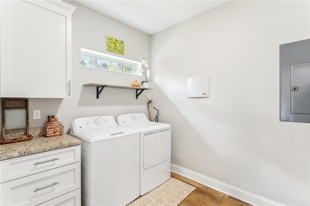 laundry area with separate washer and dryer, cabinet space, electric panel, light wood finished floors, and baseboards
