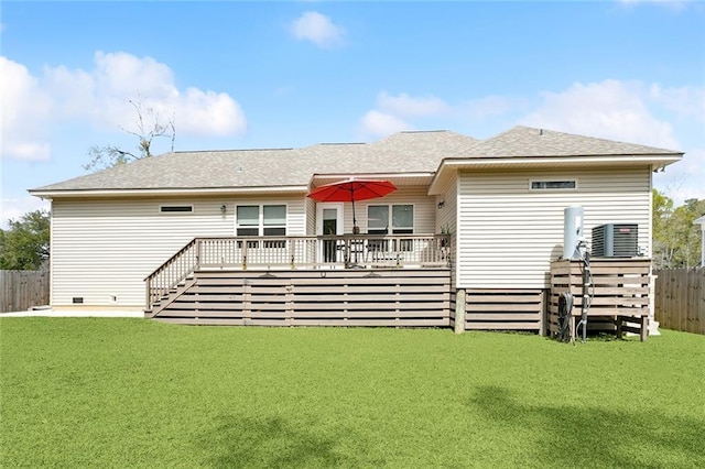 rear view of house with a deck, a yard, a fenced backyard, and roof with shingles
