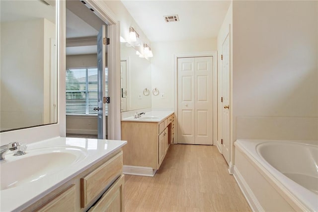 full bathroom featuring a bath, visible vents, wood finished floors, and a sink