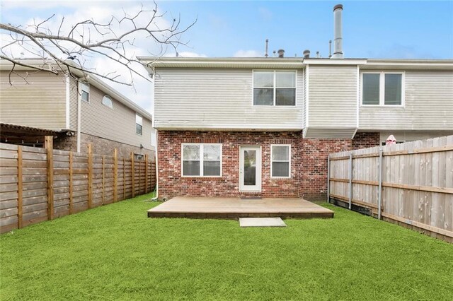 rear view of house featuring brick siding, a fenced backyard, and a lawn