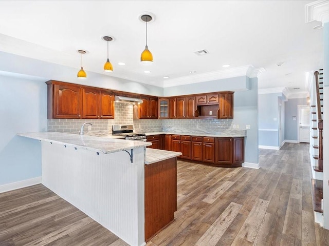 kitchen with a peninsula, stainless steel gas range, extractor fan, backsplash, and crown molding
