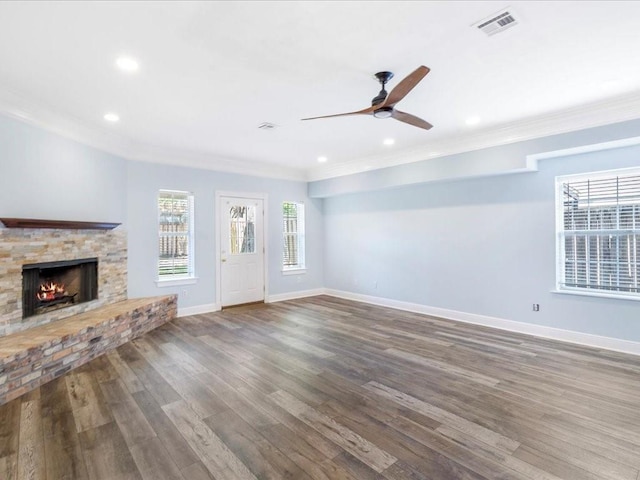 unfurnished living room with visible vents, wood finished floors, ceiling fan, a stone fireplace, and ornamental molding