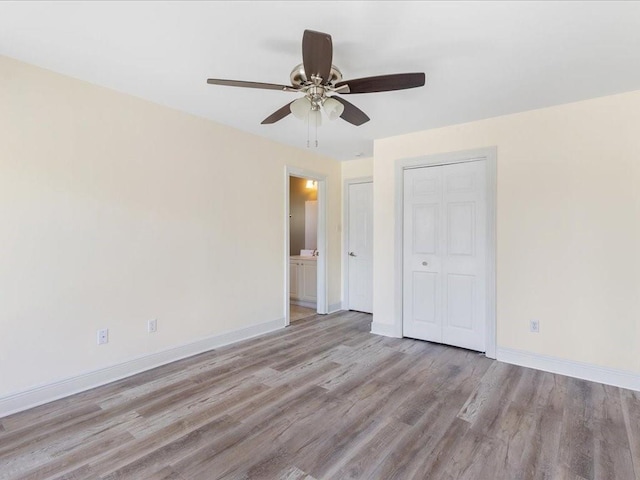 spare room with wood finished floors, a ceiling fan, and baseboards