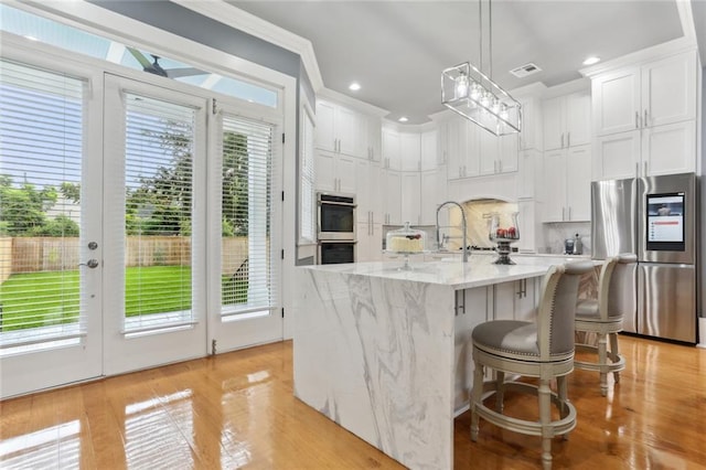736 Belleville St, New Orleans, LA 70114 - kitchen with stainless steel appliances, white cabinets, decorative backsplash, pendant lighting, and light stone counters