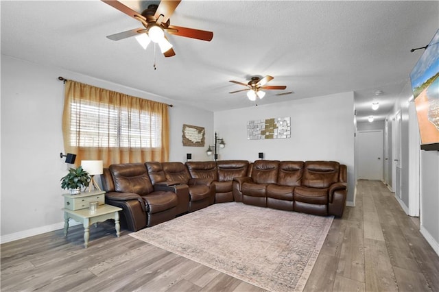 living area with visible vents, a textured ceiling, wood finished floors, baseboards, and ceiling fan