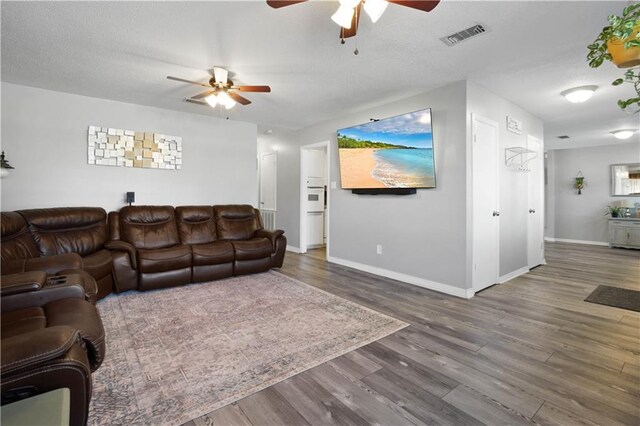 living room with visible vents, baseboards, a ceiling fan, and wood finished floors