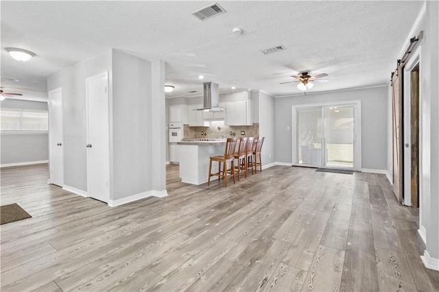 1558 Monaco Dr, Slidell, LA 70458 - living area featuring ceiling fan, a barn door, light wood-style flooring, plenty of natural light, and a textured ceiling