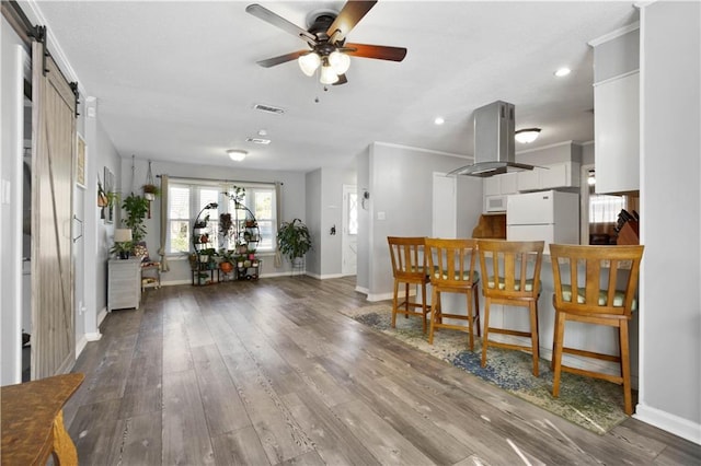 interior space with white appliances, visible vents, ceiling fan, a barn door, and island range hood