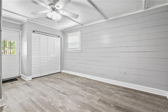 1558 Monaco Dr, Slidell, LA 70458 - unfurnished bedroom featuring baseboards, wood finished floors, wooden walls, a closet, and a ceiling fan
