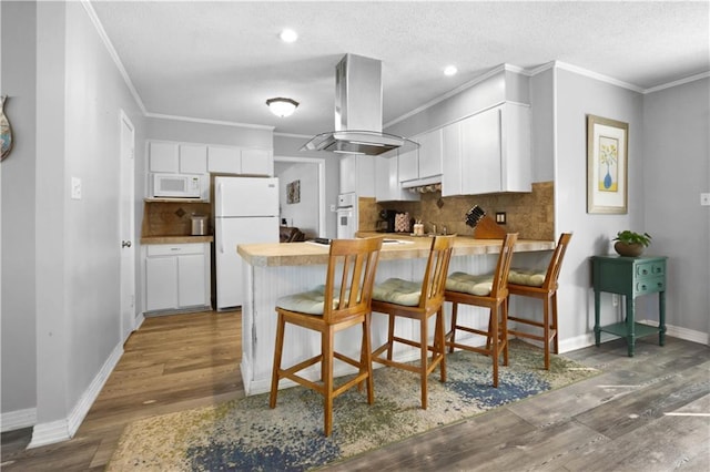 kitchen with white appliances, white cabinetry, a peninsula, and island range hood