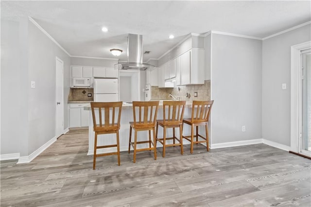 1558 Monaco Dr, Slidell, LA 70458 - kitchen featuring white appliances, ornamental molding, light wood-type flooring, a peninsula, and tasteful backsplash