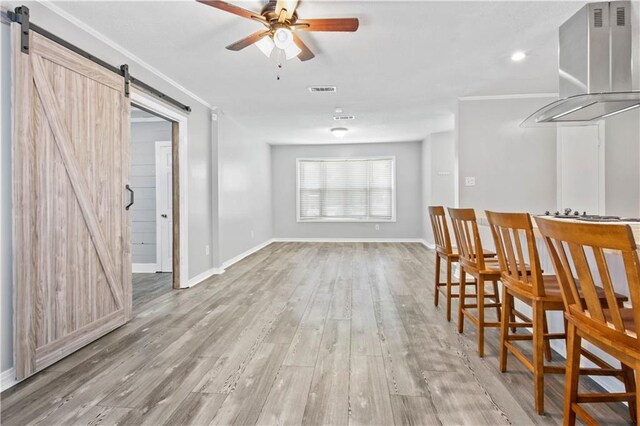 1558 Monaco Dr, Slidell, LA 70458 - dining space featuring a barn door, ceiling fan, light wood-style flooring, and baseboards