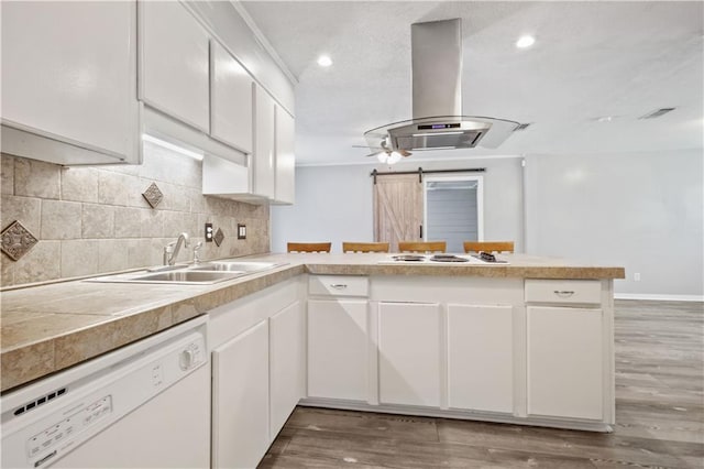 1558 Monaco Dr, Slidell, LA 70458 - kitchen with white appliances, island range hood, a peninsula, a sink, and light countertops