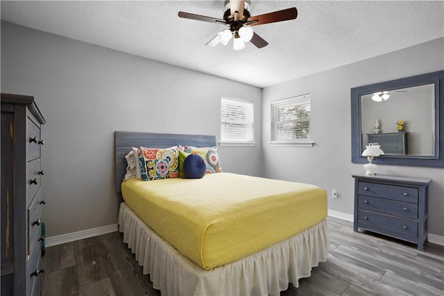 bedroom featuring baseboards, a textured ceiling, and wood finished floors