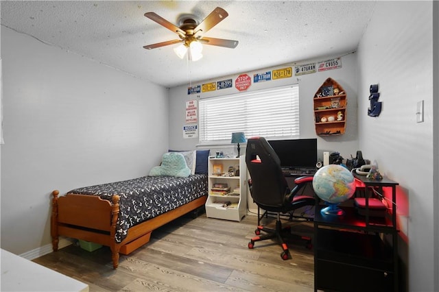 bedroom featuring baseboards, a textured ceiling, wood finished floors, and a ceiling fan