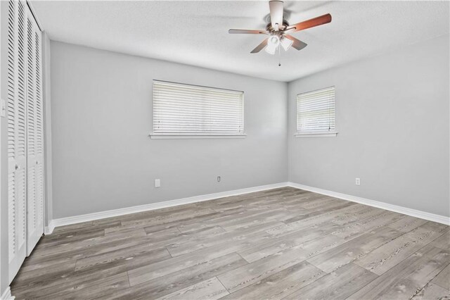1558 Monaco Dr, Slidell, LA 70458 - unfurnished bedroom with wood finished floors, baseboards, a closet, a ceiling fan, and a textured ceiling