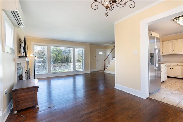 unfurnished living room with wood-type flooring, crown molding, a wall mounted AC, and baseboards