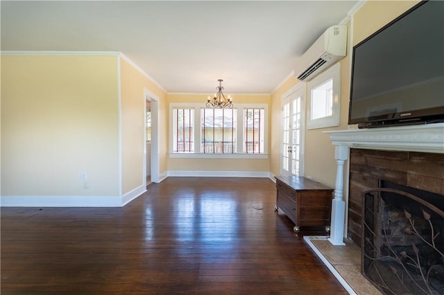 unfurnished living room featuring a wall mounted AC, dark wood finished floors, baseboards, a fireplace with raised hearth, and a notable chandelier